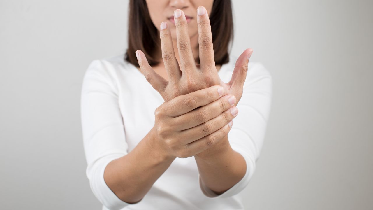 image of a woman with hand pain holding her hand