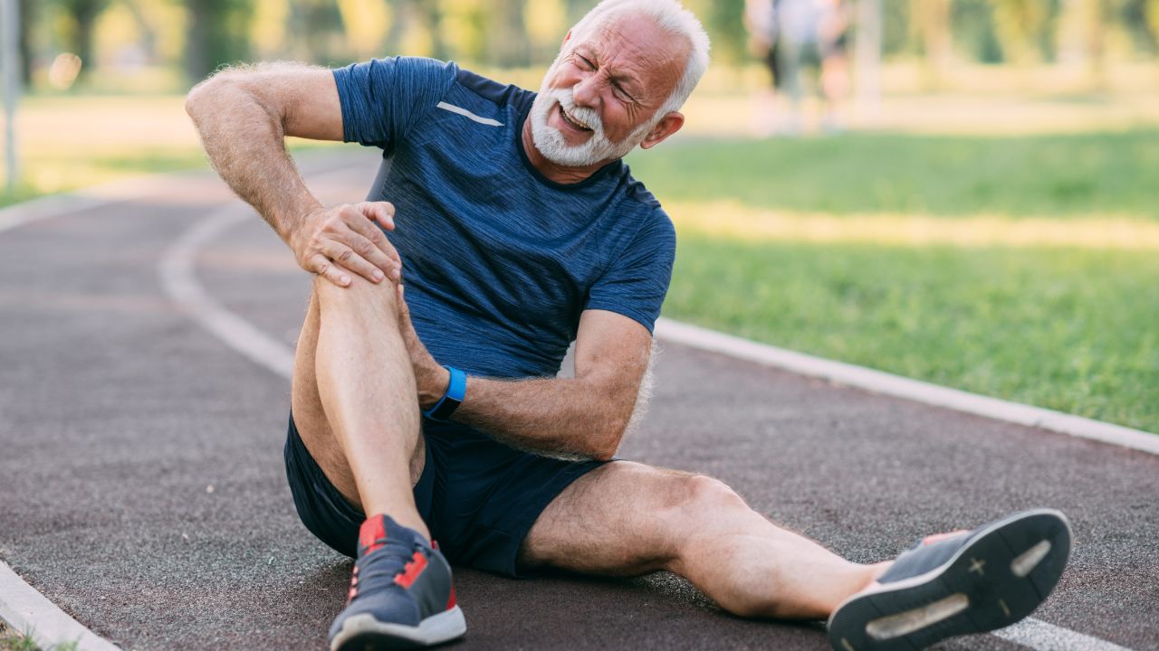 image of man in pain sitting on a running track holding his knee