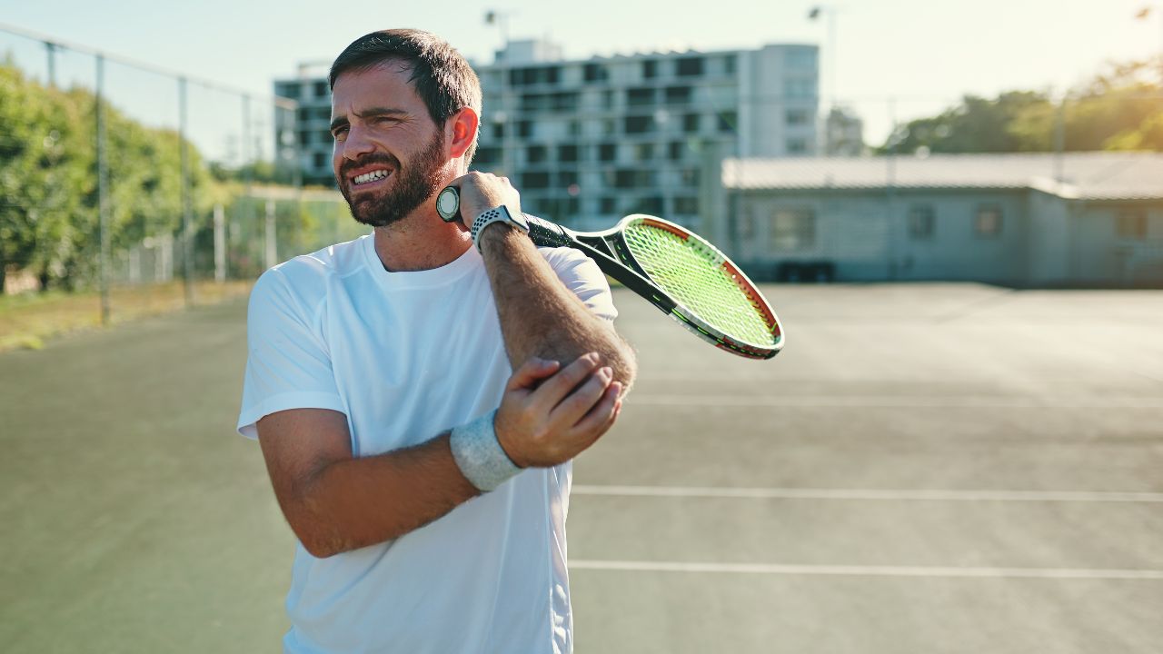 image of man playing tennis holding his elbow